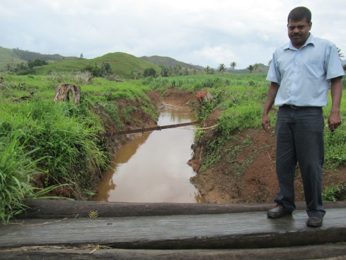 Executive Manager of LCPA Mukesh Kumar stands by a drain that was funded by Fairtrade Premiums; locals estimate that the drain saves over a thousand tonnes of cane from being flooded annually.